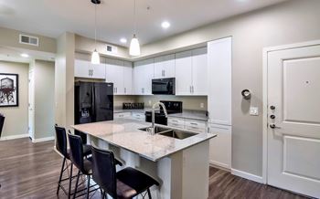 A kitchen with a white island and black chairs.